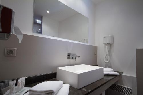 a bathroom with a white sink and a mirror at Hôtel The Originals Résidence de Rohan (EX RELAIS DU SILENCE) in Vaux-sur-Mer