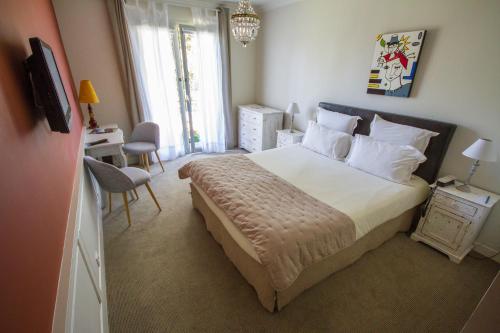 a bedroom with a bed and a desk and a television at Hôtel The Originals Résidence de Rohan (EX RELAIS DU SILENCE) in Vaux-sur-Mer