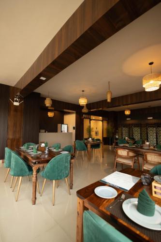 a dining room with wooden tables and green chairs at The Layover Hotel in Dimapur
