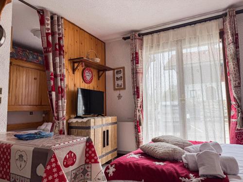 une chambre avec un lit, une télévision et une fenêtre dans l'établissement Charmant Studio Avec Terrasse By TerraAlpina, à Saint-Gervais-les-Bains