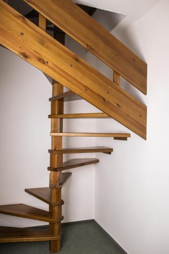 a wooden spiral staircase in a room with a white wall at Penzión Furkotka in Štrbské Pleso