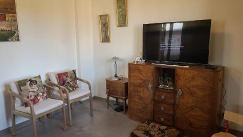 a living room with a flat screen tv and two chairs at La jolie Vue et La Maison de la Tour- Cordes-sur-Ciel in Les Cabannes