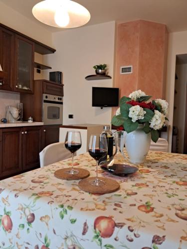 a table with two wine glasses and a vase of flowers at Roses house in Porto San Giorgio