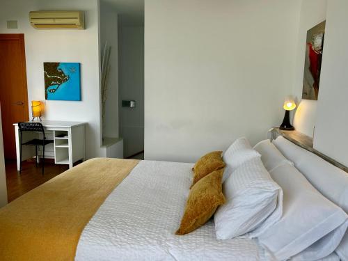 a bedroom with a bed with white sheets and pillows at Lo balconet del Delta. Àtic-dúplex vacacional. in Amposta