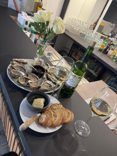 a table with two plates of oysters and a bottle of wine at Au Complex By Suprême in Laboutarié