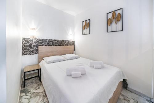 - une chambre blanche avec un lit et deux photos sur le mur dans l'établissement Studio avec terrasse et jardin arboré - 5 min hypercentre Cannes, à Cannes