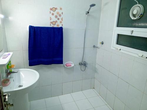 a bathroom with a shower with a blue towel at 1 Separate Bedroom and Attached Bathroom in a shared apartment in Muscat