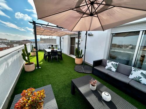 a patio with a couch and an umbrella on a balcony at Lo balconet del Delta. Àtic-dúplex vacacional. in Amposta