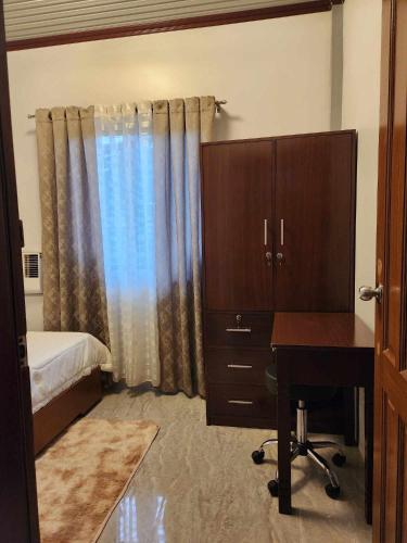 a bedroom with a desk and a bed and a dresser at Goldland Caelestis Guest House in Bacolod