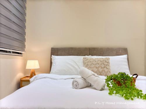 a bedroom with a white bed with a plant on it at Muji Ipoh Falim Free Parking & Free Netflix in Ipoh
