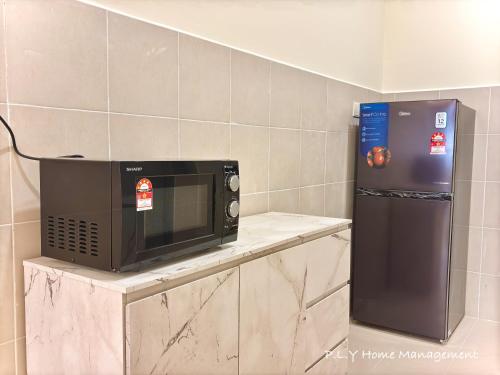 a microwave sitting on a counter next to a refrigerator at Muji Ipoh Falim Free Parking & Free Netflix in Ipoh