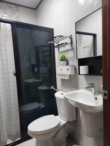 a bathroom with a toilet and a sink and a shower at Goldland Caelestis Guest House in Bacolod