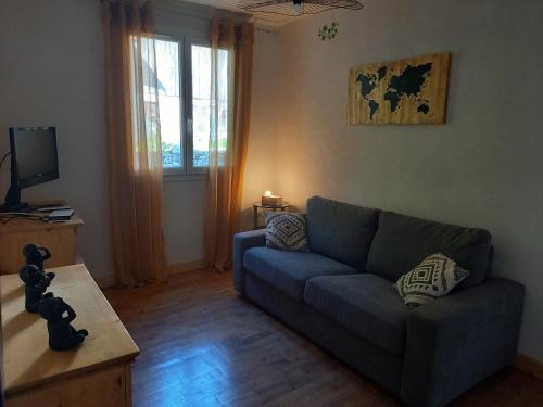 un salon avec un canapé bleu et une télévision dans l'établissement Les Coteaux de Chalain, à Doucier