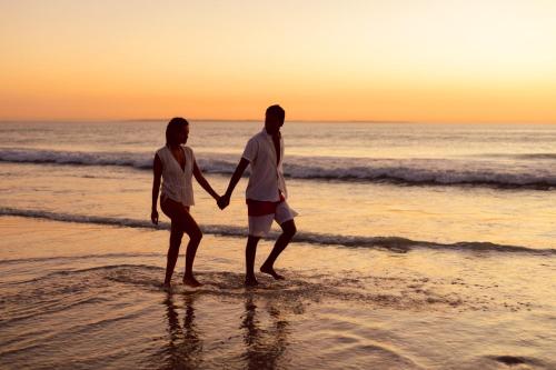 two people standing in the water on the beach at Sunset Villa - Beachfront Villa with Private Pool by Karula in Cabo Nhamua