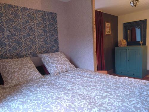a bedroom with a bed with a blue comforter at Maison p'tite Anne in Arleuf
