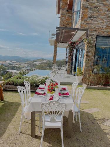 a table with white chairs and flowers on top of a house at Hồ Bơi Vô Cực - Có Thể Săn Mây Tại Giường in Da Thanh