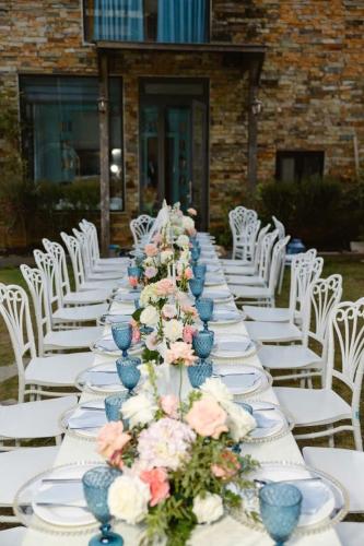 a long table with white chairs and plates and flowers at Hồ Bơi Vô Cực - Có Thể Săn Mây Tại Giường in Da Thanh