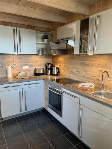 a kitchen with white cabinets and a sink at Ferienhaus "Deichglück" direkt an der Nordsee in Wesselburenerkoog