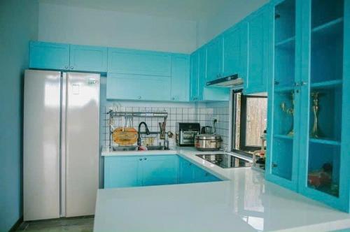 a kitchen with blue cabinets and a white refrigerator at Hồ Bơi Vô Cực - Có Thể Săn Mây Tại Giường in Da Thanh