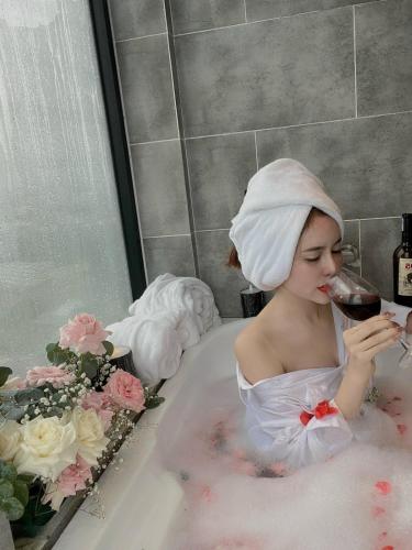 a woman sitting in a bath tub with a glass of wine at Hồ Bơi Vô Cực - Có Thể Săn Mây Tại Giường in Da Thanh