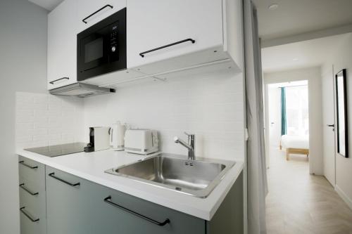 une cuisine blanche avec un évier et un micro-ondes dans l'établissement Chill-out on Private Patio in Vintage Masterpiece, à Paris