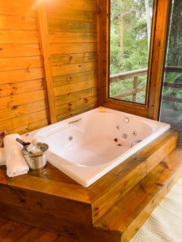 a large tub in a wooden bathroom with a window at Chalé Morada dos Tucanos in Santo Amaro da Imperatriz
