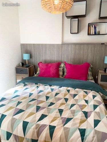 une chambre avec un grand lit avec des oreillers roses dans l'établissement Résidence Le PALM BEACH, à La Grande Motte