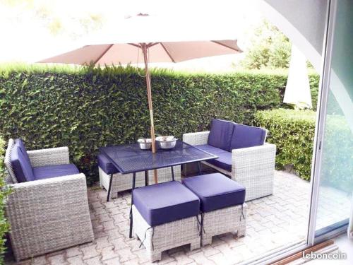 un patio avec une table, des chaises et un parasol dans l'établissement Résidence Le PALM BEACH, à La Grande Motte