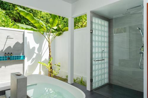 a bathroom with a tub and a tree in it at Dhigali Maldives - A Premium All-Inclusive Resort in Raa Atoll