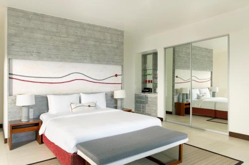 a bedroom with a large white bed and a mirror at Dhigali Maldives - A Premium All-Inclusive Resort in Raa Atoll