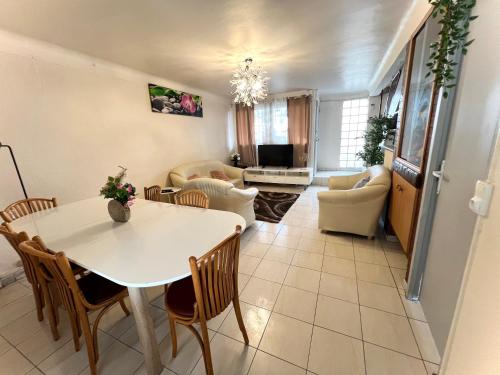 un salon avec une table et des chaises blanches dans l'établissement La maison est située en face de la gare, à Bondy