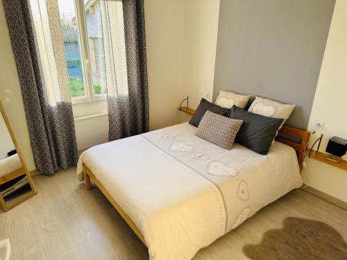 une chambre avec un grand lit avec des oreillers et une fenêtre dans l'établissement La Maison Jumelle ELM Tonneins, à Tonneins