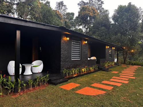a black tiny house with a garden at Viceroy Luxury Mountain Resort and Spa in Munnar
