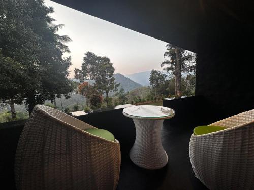 a table and chairs on a balcony with a view at Viceroy Luxury Mountain Resort and Spa in Munnar