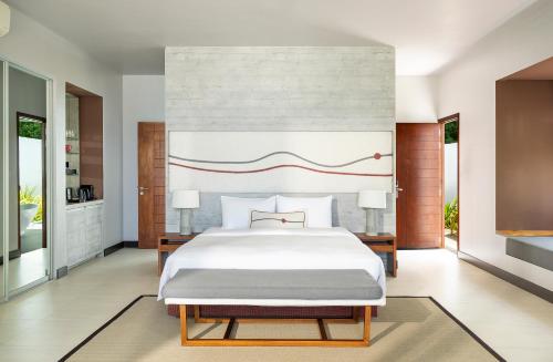 a bedroom with a large white bed and two tables at Dhigali Maldives - A Premium All-Inclusive Resort in Raa Atoll