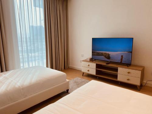 a bedroom with a television on a dresser with two beds at 2BR Soul Beach Mamsha Al Saadiyat Full Apartment in Abu Dhabi