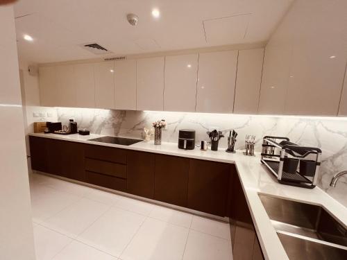 a kitchen with white cabinets and a sink at 2BR Soul Beach Mamsha Al Saadiyat Full Apartment in Abu Dhabi