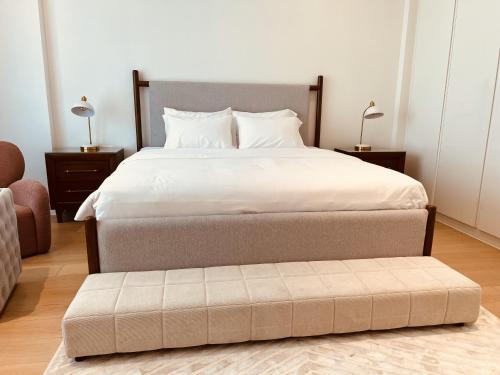 a bedroom with a large bed with a ottoman at 2BR Soul Beach Mamsha Al Saadiyat Full Apartment in Abu Dhabi