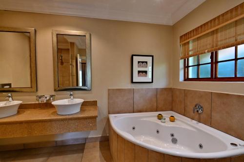 a large bathroom with a tub and two sinks at Champagne Castle Hotel in Champagne Valley