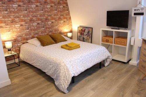 a bedroom with a bed and a brick wall at Studio 211 au cœur du campus de Belle Beille in Angers
