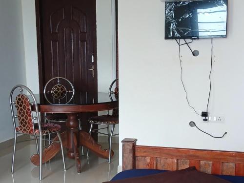 a dining room with a table and a tv at Roamwander Apartments in Vagamon