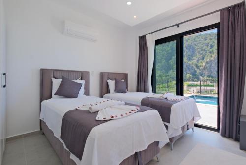 two beds in a room with a large window at Villa Montana 1 in Fethiye