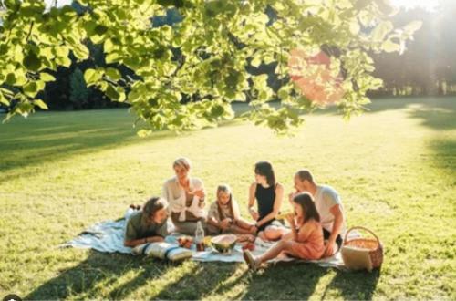 a group of people sitting on a blanket in the grass at lodge for all ages in Aviemore