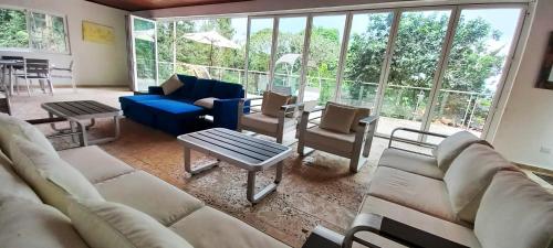 a living room with couches and chairs and windows at Summit View Guest House in Los Altos de Cerro Azul