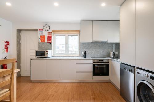 a kitchen with white cabinets and a window at Casa da Petisqueira 54, Paredes-Oporto in Rebordosa