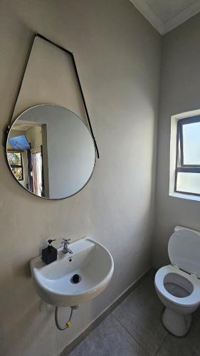 a bathroom with a sink and a mirror and a toilet at Jacuzzi, Airport, St George's Park in Gqeberha