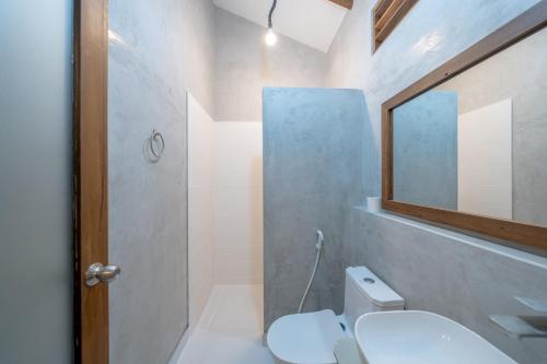 a bathroom with a white toilet and a mirror at Brickwood Rasdhoo- Beach front in Rasdu