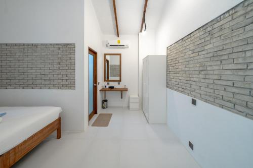 a bedroom with a brick wall and a bed at Brickwood Rasdhoo- Beach front in Rasdu
