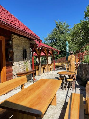 a man standing next to wooden tables and benches at Penzion Pulčínské Skály in Pulčín