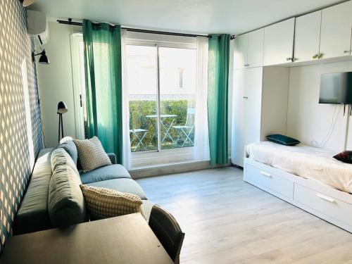 - un salon avec un canapé, un lit et une fenêtre dans l'établissement Le Joli Petit Morny Hypercentre, à Deauville